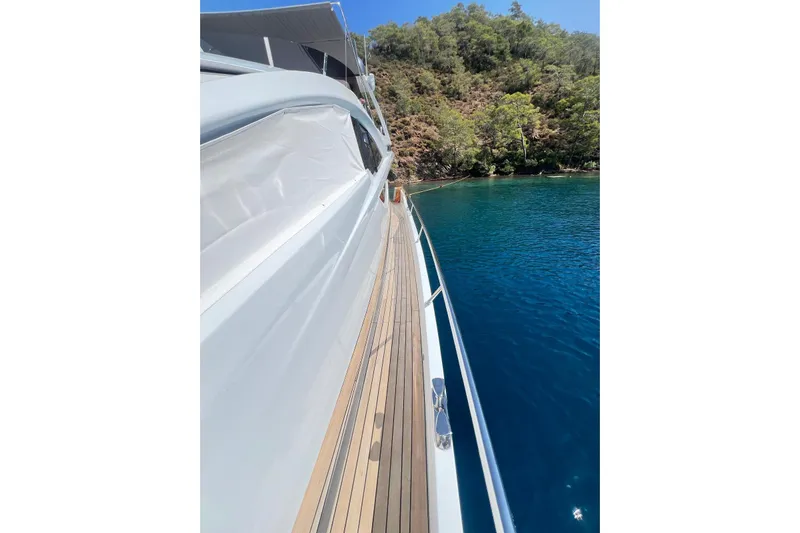  Yacht Photos Pics Side view of 2010 Numarine 78 yacht on clear blue water near lush green shoreline.