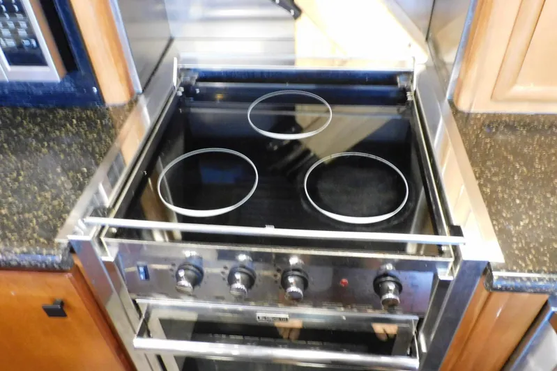 Waterdog Yacht Photos Pics Stovetop in 2002 Carver 570 Voyager Pilothouse kitchen, featuring three burners and control knobs.