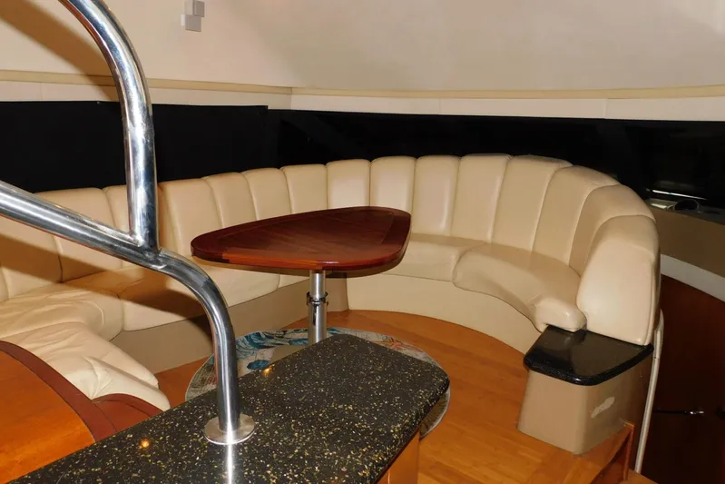 Waterdog Yacht Photos Pics Luxurious interior of 2002 Carver 570 Voyager Pilothouse with curved seating and wooden table.