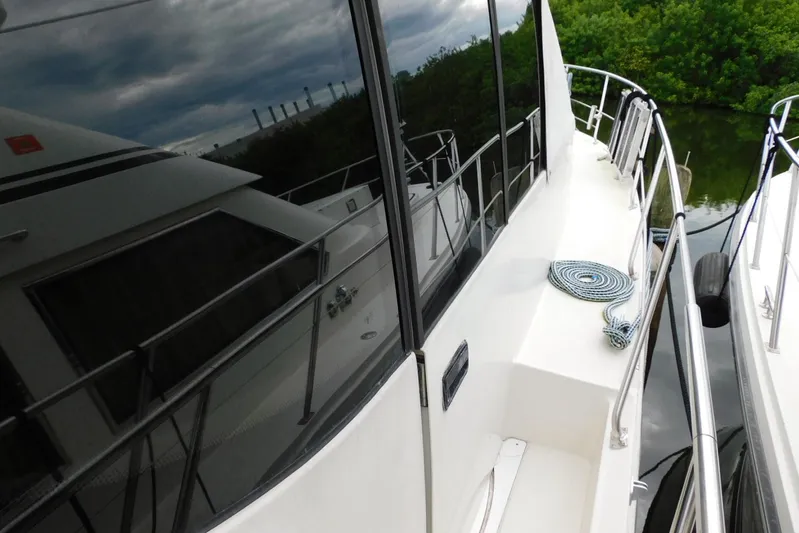 Waterdog Yacht Photos Pics 2002 Carver 570 Voyager Pilothouse yacht docked, reflecting water and greenery.