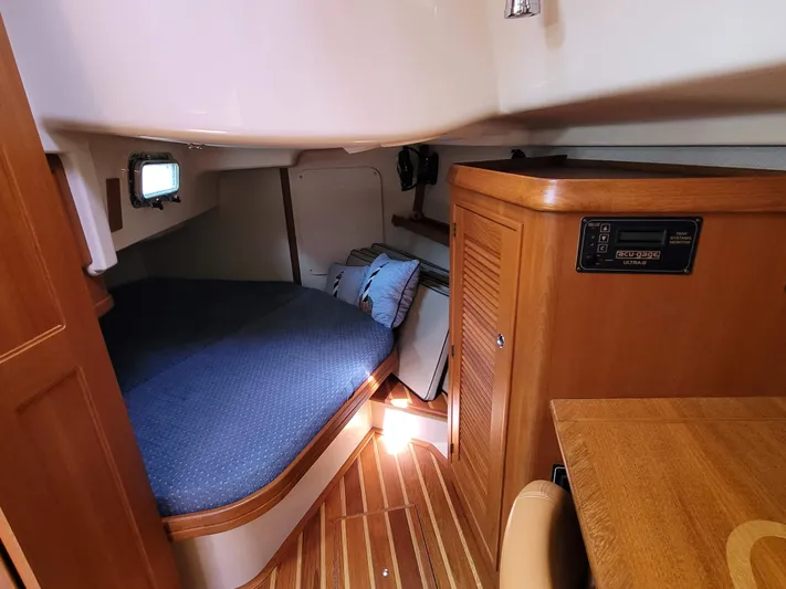 Mango Lll Yacht Photos Pics Cozy cabin interior of 2006 Island Packet 370 sailboat with wooden furnishings and blue bedding.