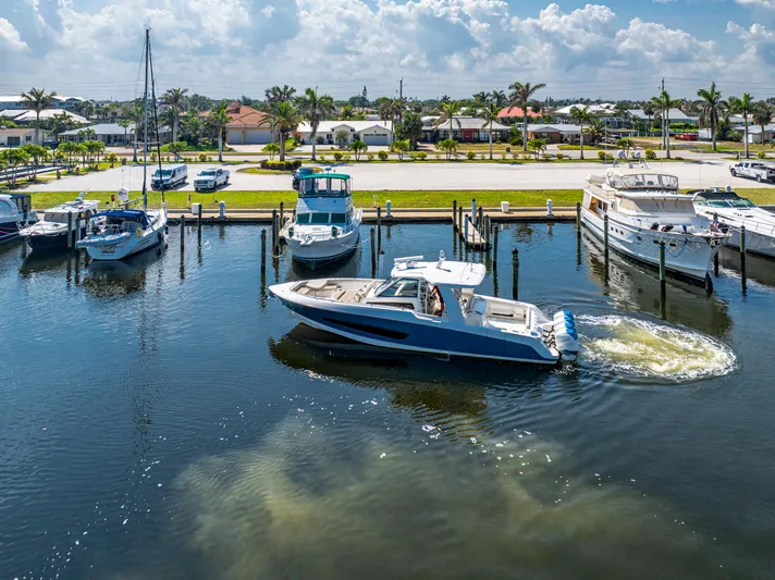 Jet Lag Yacht Photos Pics 2019 Boston Whaler 420 Outrage navigating marina, surrounded by boats and waterfront homes.