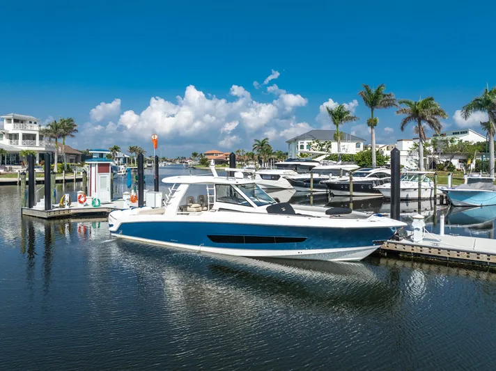 Jet Lag Yacht Photos Pics 2019 Boston Whaler 420 Outrage docked in a sunny marina with palm trees.