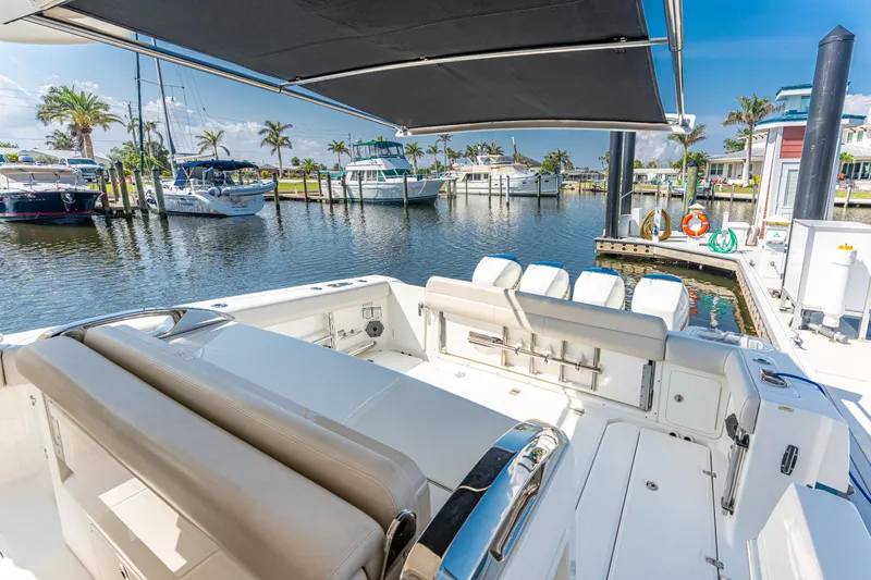 Jet Lag Yacht Photos Pics 2019 Boston Whaler 420 Outrage docked, featuring spacious seating and canopy, in a sunny marina.