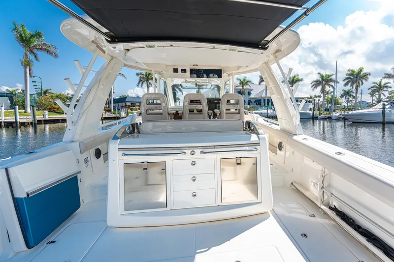 Jet Lag Yacht Photos Pics 2019 Boston Whaler 420 Outrage boat interior with seating and storage, docked by palm trees.