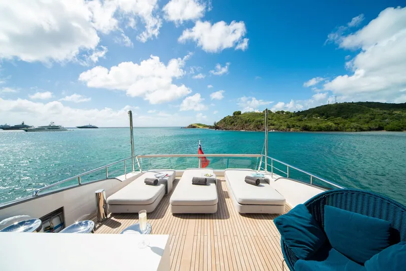 Squalo Yacht Photos Pics Luxurious Sanlorenzo SL86 yacht deck with sun loungers, overlooking serene blue waters and lush island.