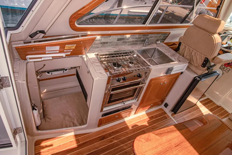 Arrow II Yacht Photos Pics Compact kitchen in 2019 Aspen C107 boat with stove, sink, and wooden cabinetry.