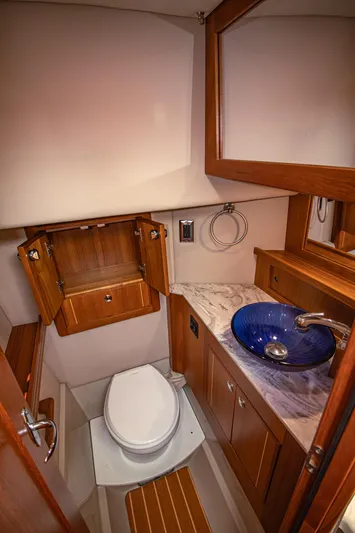 Arrow II Yacht Photos Pics 2019 Aspen C107 yacht bathroom with wooden cabinets, marble countertop, and blue vessel sink.