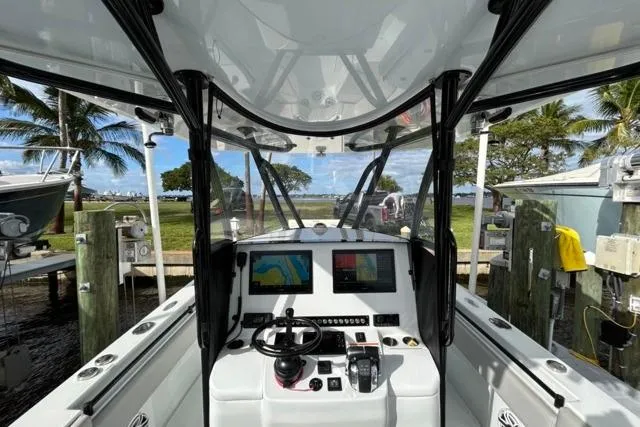  Yacht Photos Pics 2023 Contender 32 ST boat cockpit with advanced navigation system, docked near palm trees.