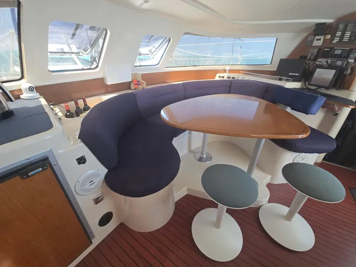 Think Twice Yacht Photos Pics Interior of 2005 Fountaine Pajot Lavezzi Maestro catamaran with curved seating and wooden table.