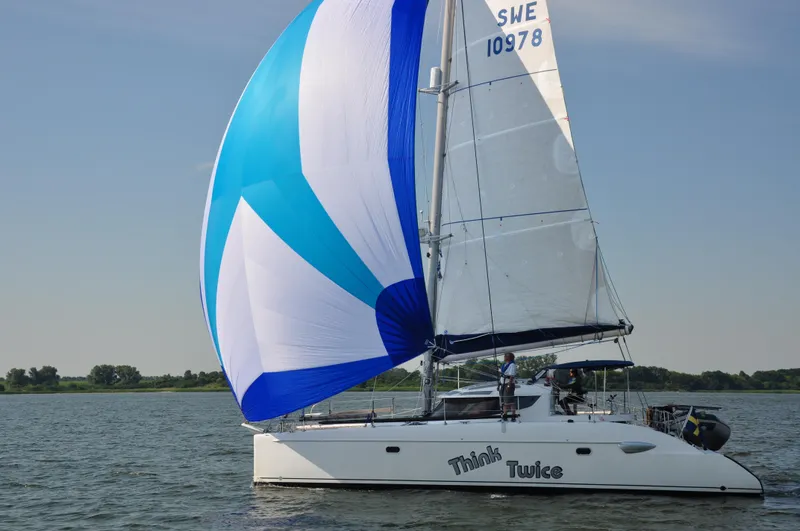 Think Twice Yacht Photos Pics 2005 Fountaine Pajot Lavezzi Maestro catamaran sailing with blue and white spinnaker.