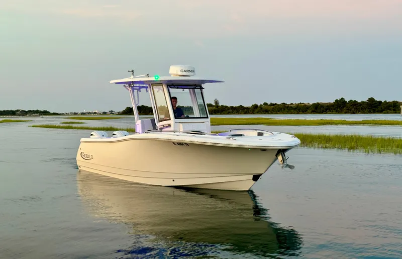  Yacht Photos Pics 2024 Robalo R270 Center Console boat cruising on calm waters at sunset.