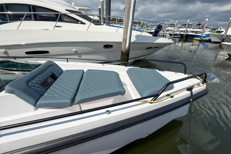 Maverick Yacht Photos Pics 2023 Axopar 37 XC AFT CABIN with cushioned seating, docked at a marina.