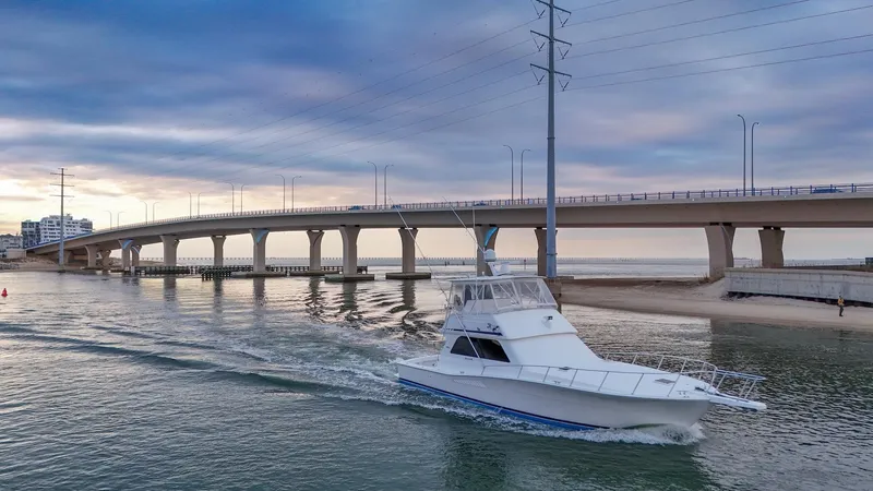  Yacht Photos Pics 1998 Viking 47 Convertible yacht cruising under a bridge at sunset.