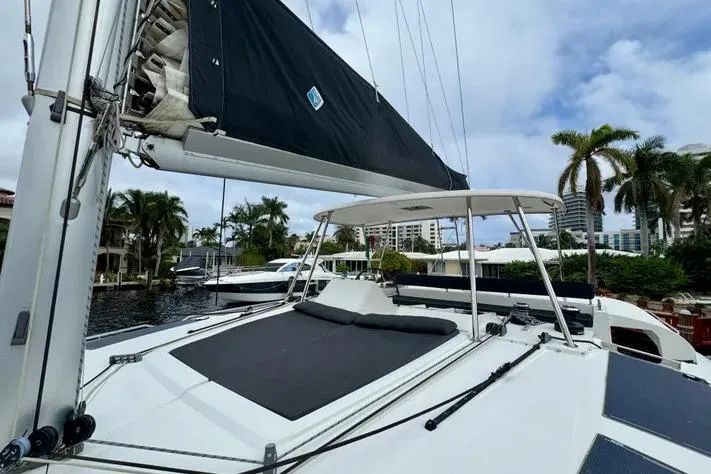 Yacht Photos Pics 2019 Lagoon 450 catamaran docked, featuring sleek design and spacious deck under a cloudy sky.