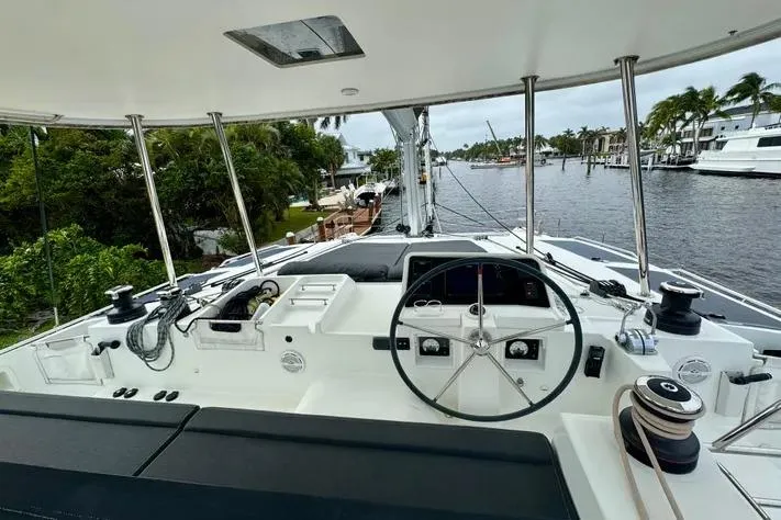  Yacht Photos Pics Cockpit view of 2019 Lagoon 450 catamaran, featuring steering wheel and marina backdrop.