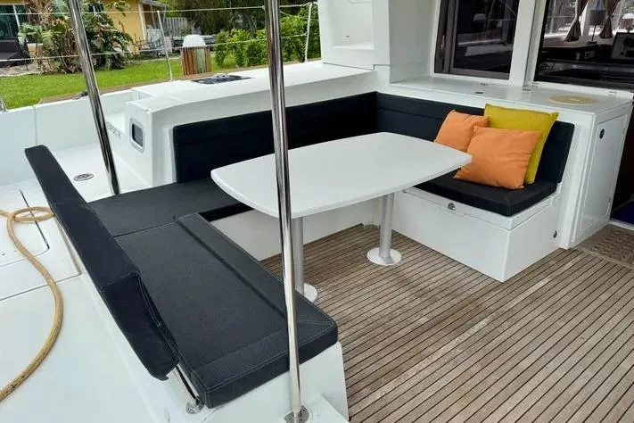  Yacht Photos Pics 2019 Lagoon 450 yacht interior with cushioned seating and table on wooden deck.