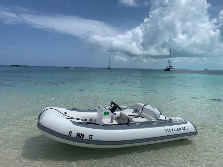 Tranquility Yacht Photos Pics Inflatable boat on clear water with distant sailboats, under a partly cloudy sky.