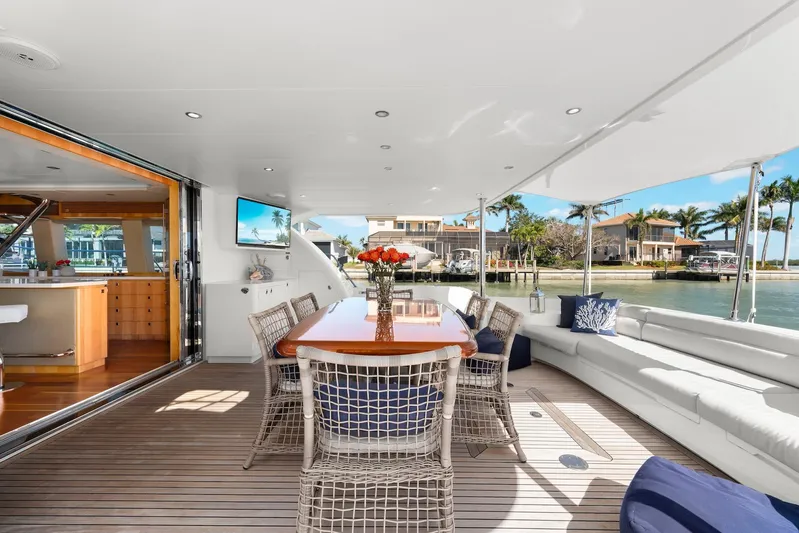 Tranquility Yacht Photos Pics Luxurious Horizon PC60 yacht deck with dining area, wicker chairs, and waterfront view.