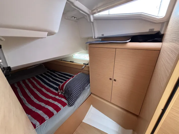 Khushali Yacht Photos Pics Cozy cabin interior of 2019 Jeanneau Sun Odyssey 419 with striped bedding and wooden cabinetry.