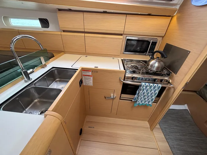 Khushali Yacht Photos Pics Modern kitchen in 2019 Jeanneau Sun Odyssey 419 yacht with stove, sink, and microwave.