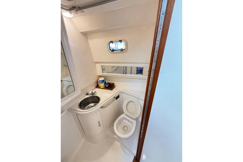 Sea Dated Yacht Photos Pics Compact bathroom in a 1996 Cabo 35 boat, featuring a sink, toilet, and small window.