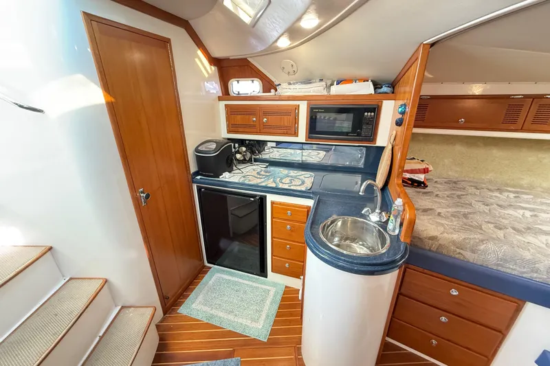 Sea Dated Yacht Photos Pics Interior of a 1996 Cabo 35 boat featuring a compact kitchen with wood accents.