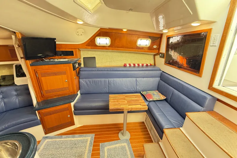 Sea Dated Yacht Photos Pics Interior of a 1996 Cabo 35 boat with blue seating and wooden accents.