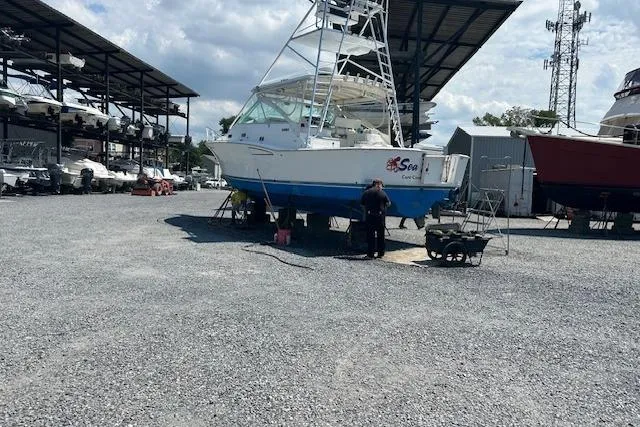 Sea Dated Yacht Photos Pics 1996 Cabo 35 boat in a marina, under maintenance, surrounded by other boats and structures.