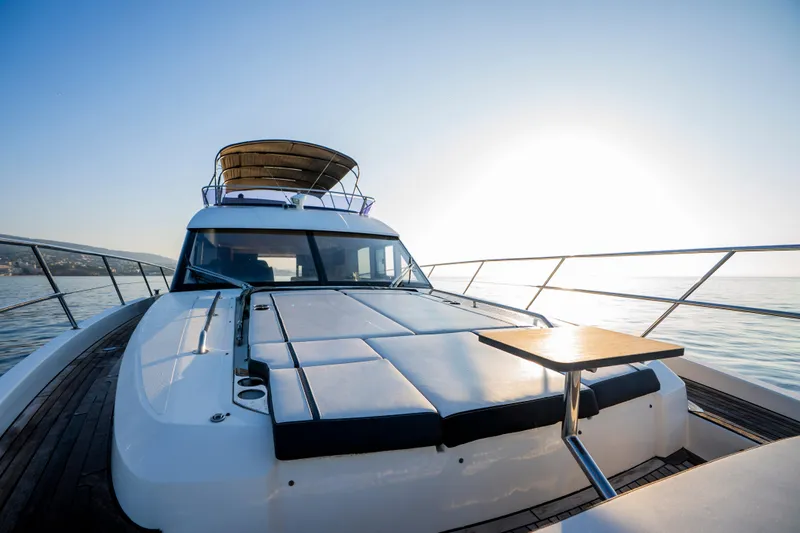 Valluga Yacht Photos Pics Luxurious 2018 Bavaria R55 yacht deck with sunbathing area and table, cruising at sunset.