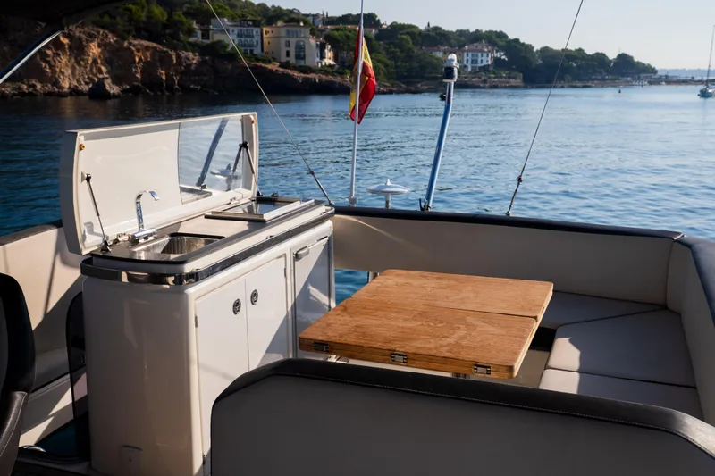Valluga Yacht Photos Pics 2018 Bavaria R55 yacht interior with kitchenette and seating area, overlooking scenic coastal view.