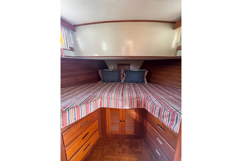 Good Enough Yacht Photos Pics Cozy cabin interior of 1990 Grand Banks 46 Classic with striped bedding and wooden storage.