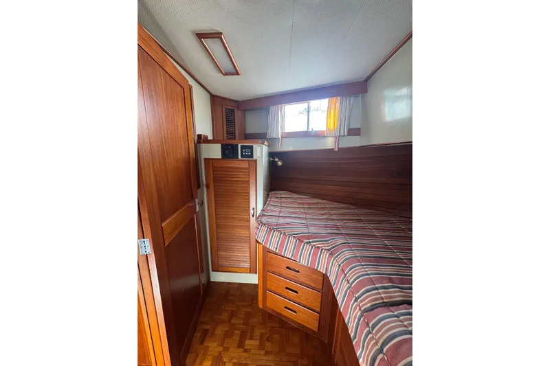 Good Enough Yacht Photos Pics Cozy cabin interior of 1990 Grand Banks 46 Classic yacht with wood paneling and striped bedding.