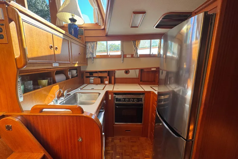 Good Enough Yacht Photos Pics Interior of 1990 Grand Banks 46 Classic yacht kitchen with wood cabinetry and stainless steel appliances.