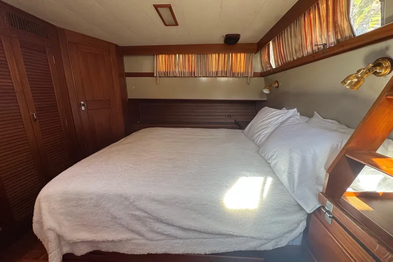 Good Enough Yacht Photos Pics Cozy bedroom interior of 1990 Grand Banks 46 Classic yacht with wooden accents and soft lighting.