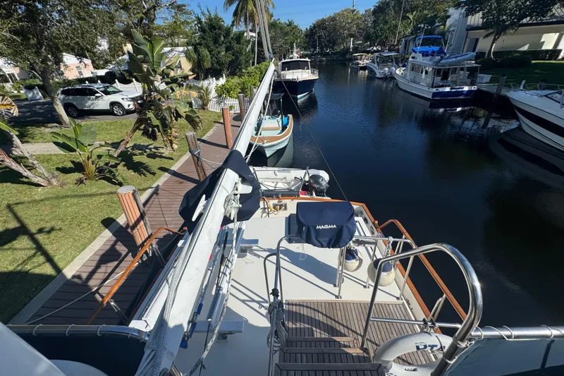 Good Enough Yacht Photos Pics Grand Banks 46 Classic yacht docked in a serene canal, surrounded by lush greenery.