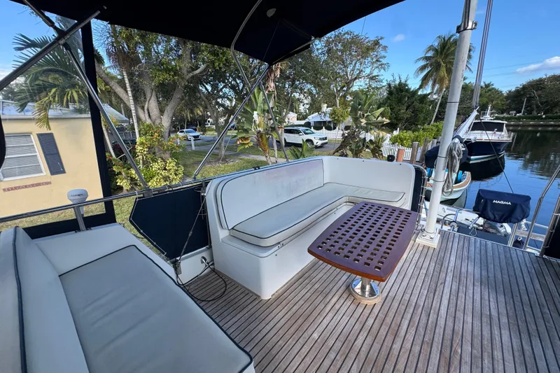 Good Enough Yacht Photos Pics Deck of 1990 Grand Banks 46 Classic yacht with seating and table, docked near lush greenery.