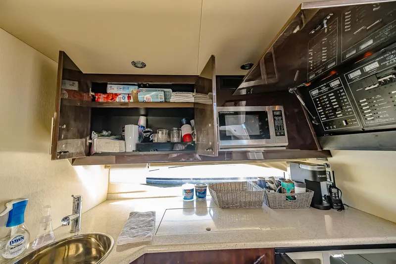  Yacht Photos Pics 2016 Regal 46 Sport Coupe kitchen with open cabinets, microwave, and countertop essentials.