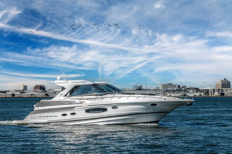  Yacht Photos Pics 2016 Regal 46 Sport Coupe cruising on water with city skyline in background.