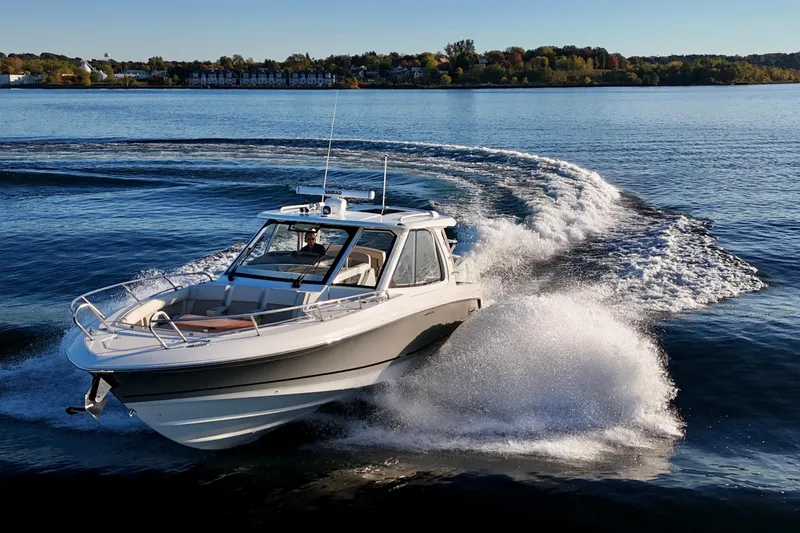  Yacht Photos Pics 2024 Boston Whaler 380 Realm cruising on a scenic lake with a wake trail.