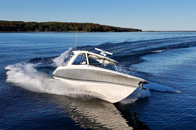  Yacht Photos Pics 2024 Boston Whaler 380 Realm cruising on a serene lake under clear blue skies.