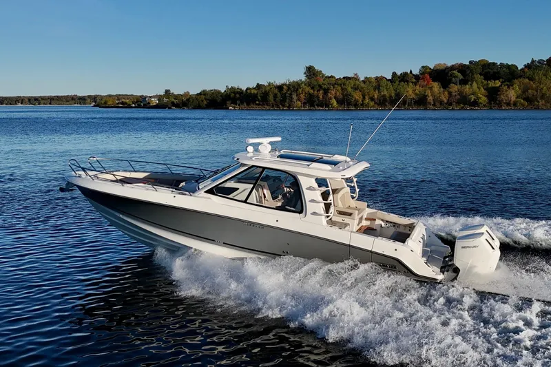  Yacht Photos Pics 2024 Boston Whaler 380 Realm cruising on a scenic lake under clear skies.