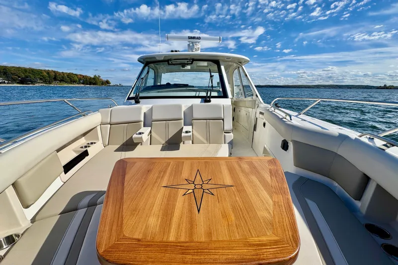  Yacht Photos Pics 2024 Boston Whaler 380 Realm boat interior with wooden table, on a sunny day at sea.