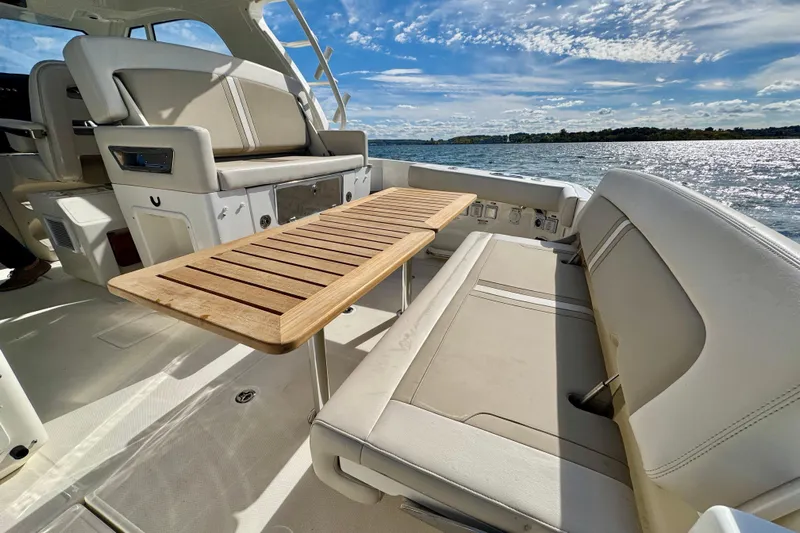  Yacht Photos Pics 2024 Boston Whaler 380 Realm interior with seating and wooden table, overlooking serene waters.