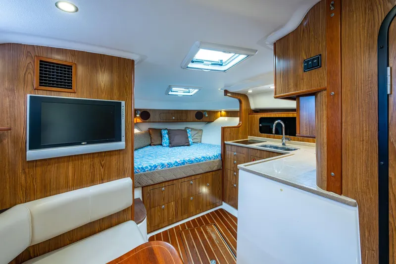Bottoms Up II Yacht Photos Pics Luxurious 2009 Pursuit OS 375 Offshore cabin interior with wood finish, bed, and kitchenette.