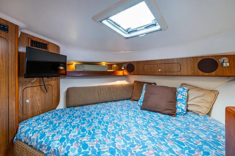 Bottoms Up II Yacht Photos Pics Cozy cabin interior of 2009 Pursuit OS 375 Offshore with bed, TV, and skylight.