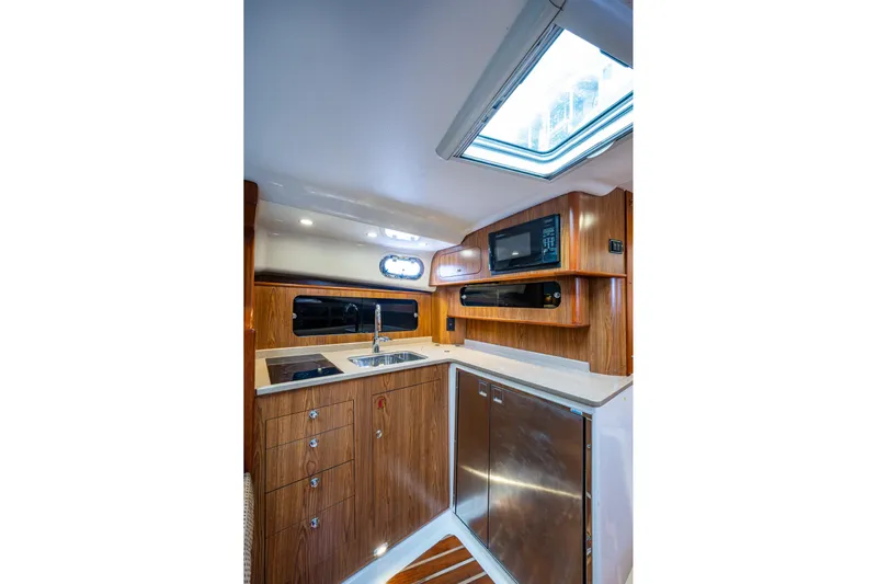 Bottoms Up II Yacht Photos Pics 2009 Pursuit OS 375 Offshore yacht kitchen with wood cabinetry, stainless steel appliances, and skylight.