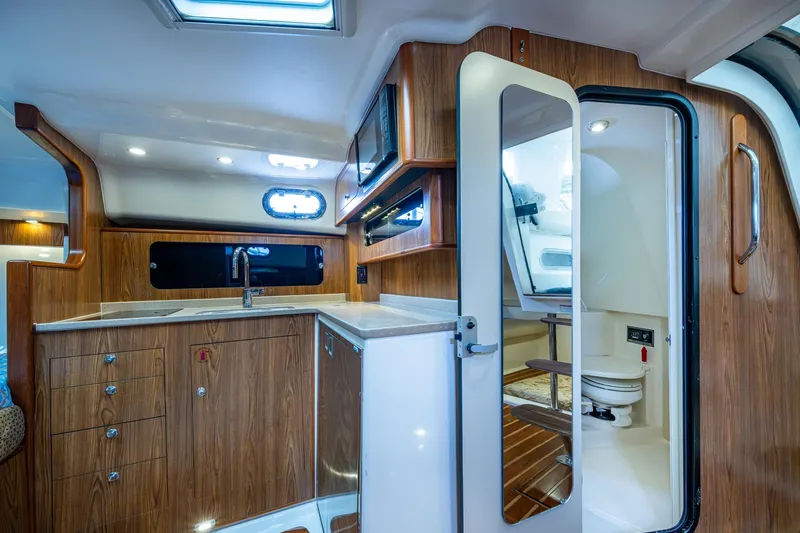Bottoms Up II Yacht Photos Pics 2009 Pursuit OS 375 Offshore yacht interior with wood cabinetry and compact bathroom.