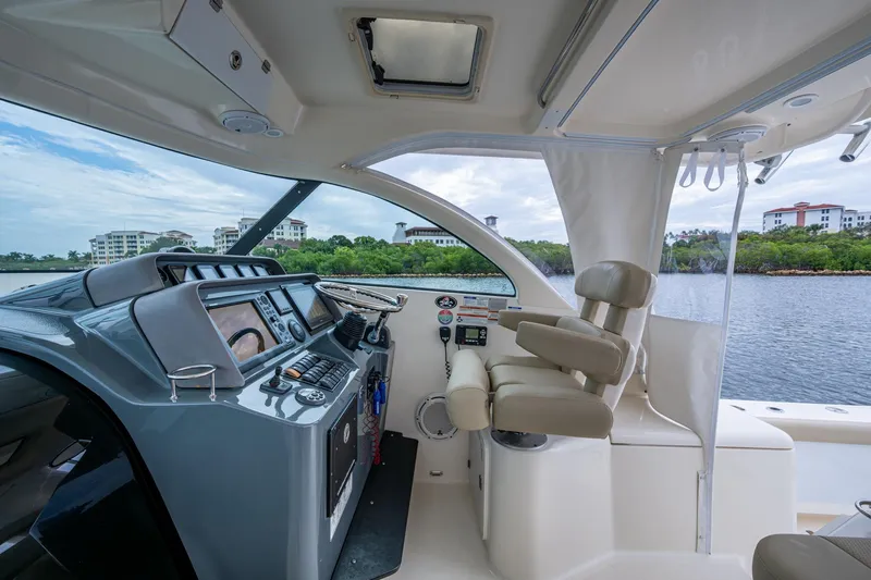 Bottoms Up II Yacht Photos Pics 2009 Pursuit OS 375 Offshore boat interior with helm, controls, and seating by the water.