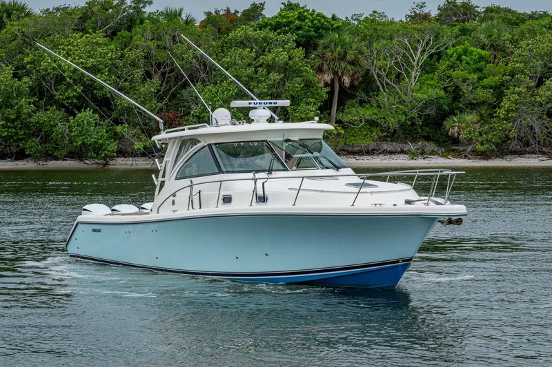 Bottoms Up II Yacht Photos Pics 2009 Pursuit OS 375 Offshore boat cruising near lush green shoreline.